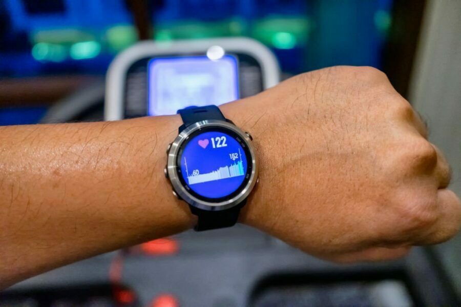 Bărbat care rulează pe o bandă de alergare cu un ceas sportiv încheiat la mână.