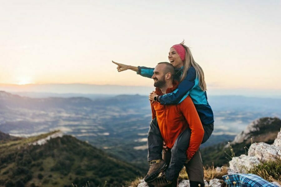 Cuplu fericit, bărbatul își ține iubita pe spate, iar ea arată cu degetul. Imaginea nu are legătură cu produsul.