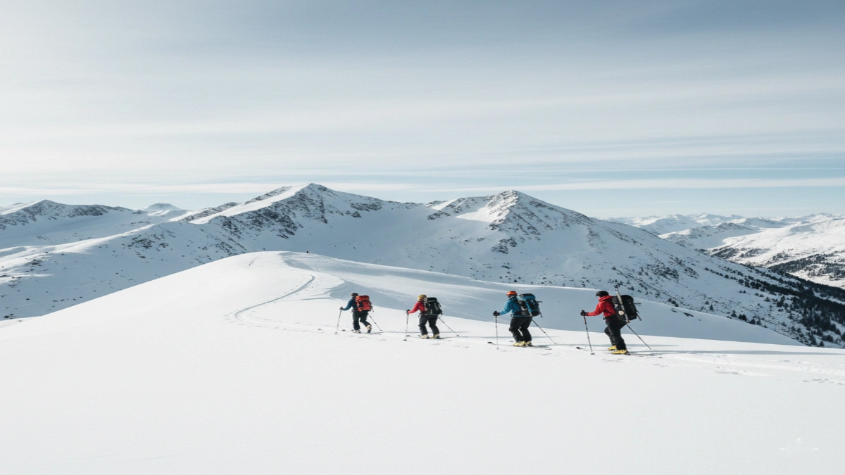 Grup de schiori în tură urcând pe o creastă montană acoperită de zăpadă