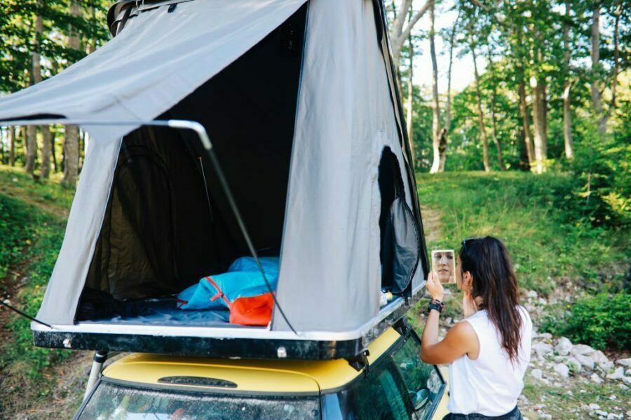 Tânără verificând instalarea cortului de plafon auto în natură