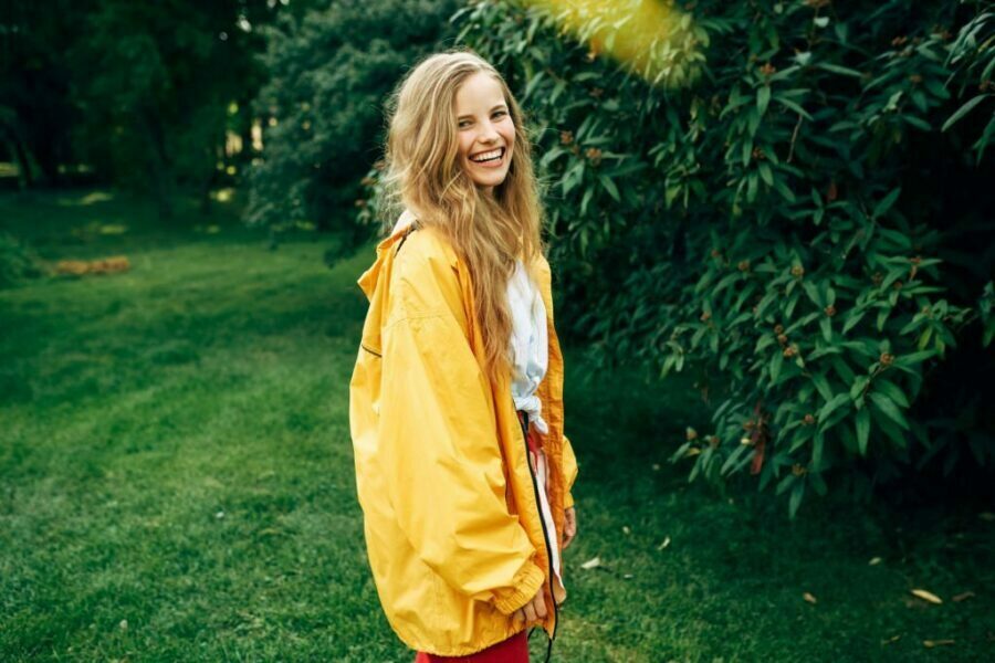 Tânără zâmbitoare într-o jachetă de ploaie galbenă pentru femei