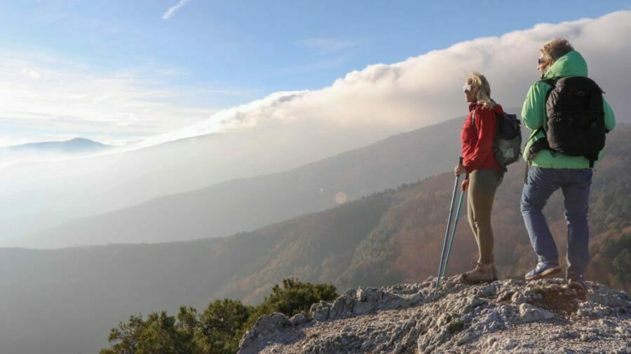 Femeie purtând pantaloni de drumeție pentru dame și explorând munții și văile înconjurătoare.