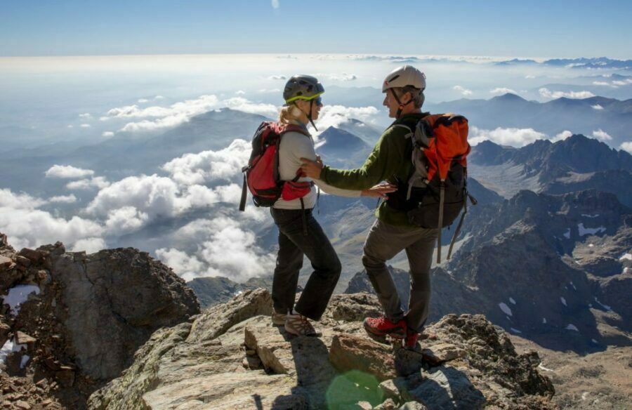 Pereche de pantaloni de drumeție pentru dame pregătiți pentru aventurile în natură, cu un cadru pitoresc cu nori și munți în depărtare.