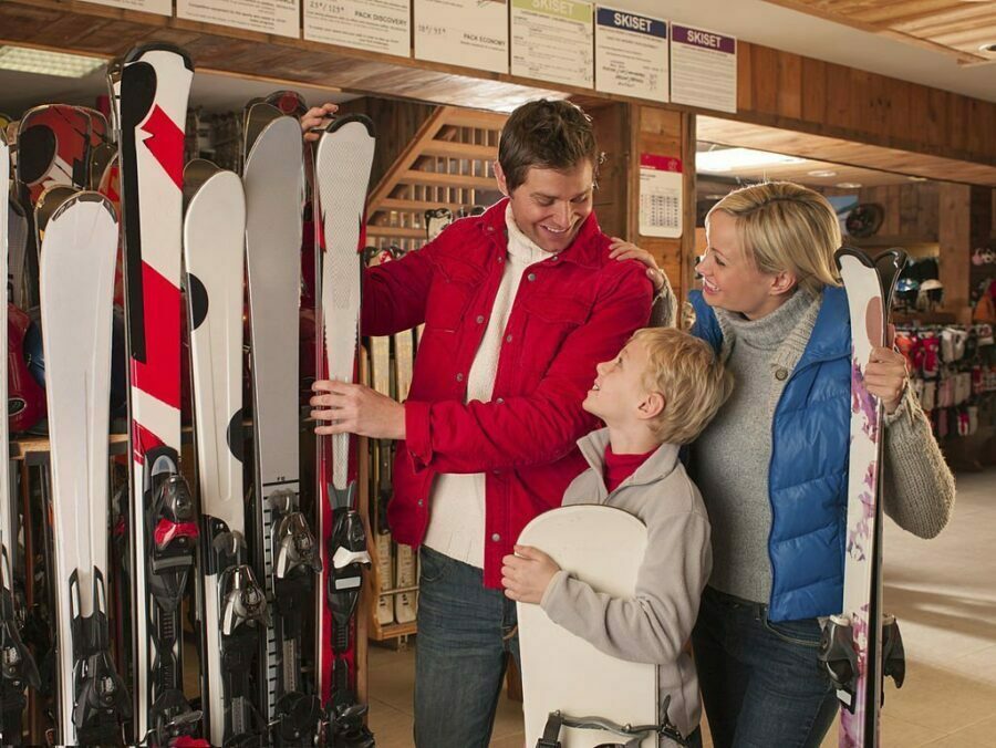 Familie alegând schiuri cu legături într-un magazin de echipament de iarnă