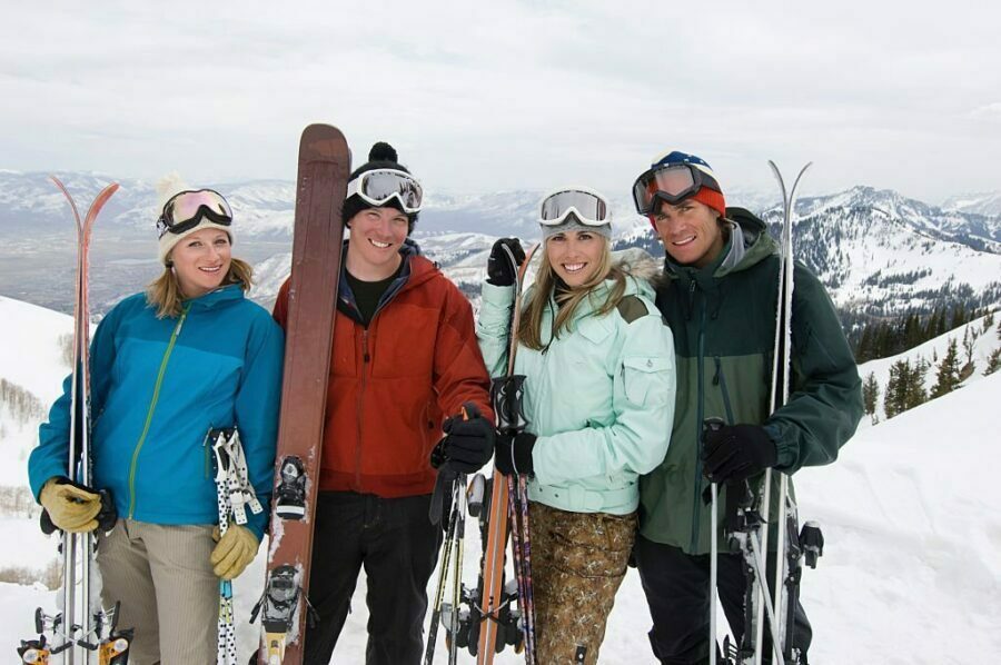 Grup de prieteni schiori cu geci colorate pe un fundal montan.