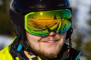 Ochelari de ski reflectorizanți cu lentile verzi pe un schior cu cască neagră