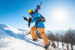 Schior bărbat echipat cu pantaloni de ski portocalii de performanță pe munte