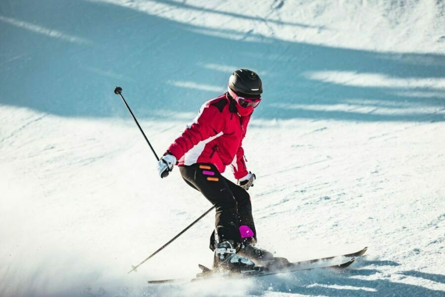 Schioare în pantaloni de ski pentru dame de culoare roșie, demonstrând agilitate și stil pe pârtia înzăpezită