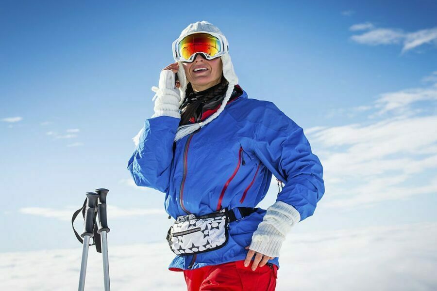 Femeie schior cu ochelari de ski cu lentile reflectorizante portocalii, echipament de schi albastru și roșu