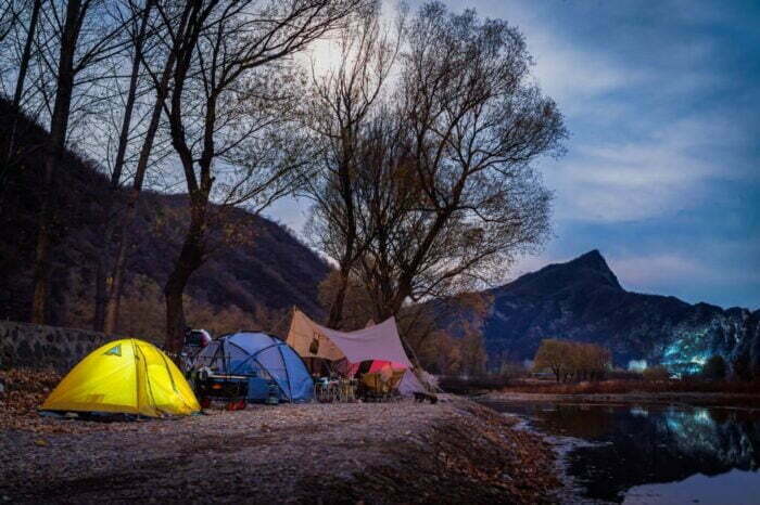 Imagine cu o tabără de camping într-o noapte de toamnă târzie, cu un cer înstelat și un râu liniștit în apropiere.