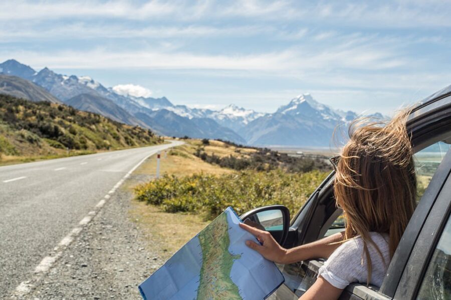Tânără femeie în mașină, verificând harta pentru indicații de orientare
