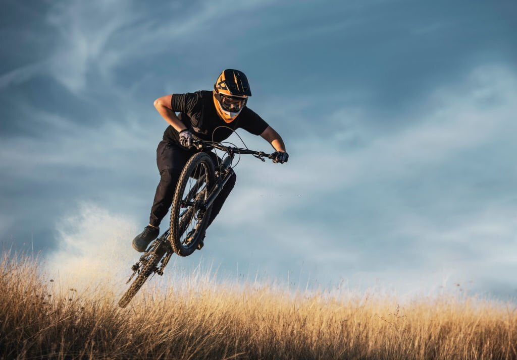 Biciclist de munte priceput care sări - imagine ilustrativă pentru ghidul de achiziționare a căștilor de mountain bike