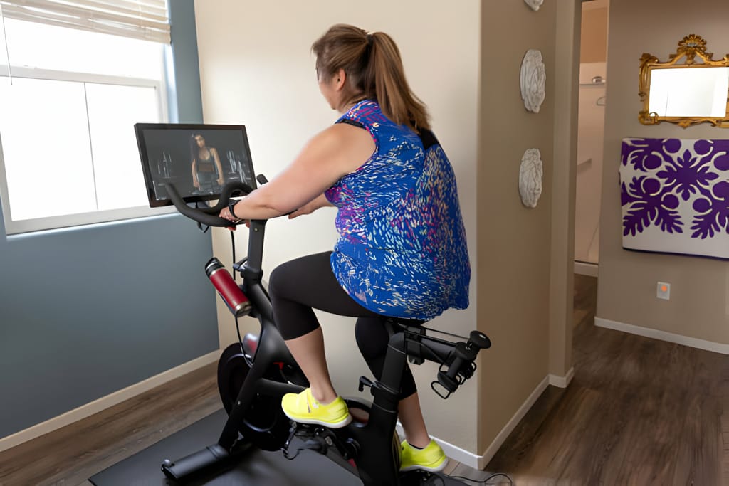 Femeie antrenându-se pe o bicicletă fitness cu ecran digital la domiciliu