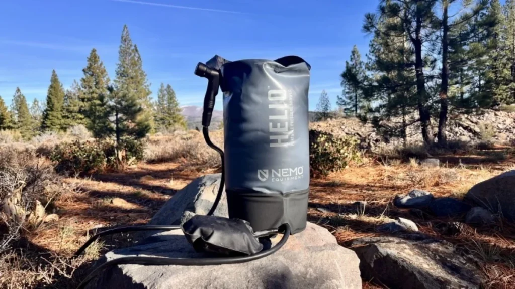 Duș portabil NEMO Helio așezat pe o stâncă într-un peisaj montan