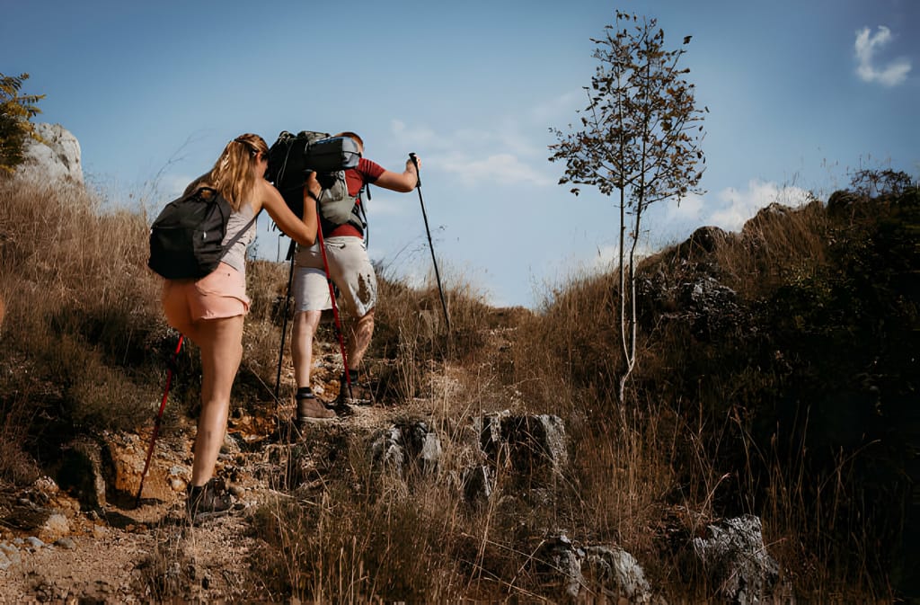 Drumeți în echipament complet folosind bețe de trekking pe un traseu montan
