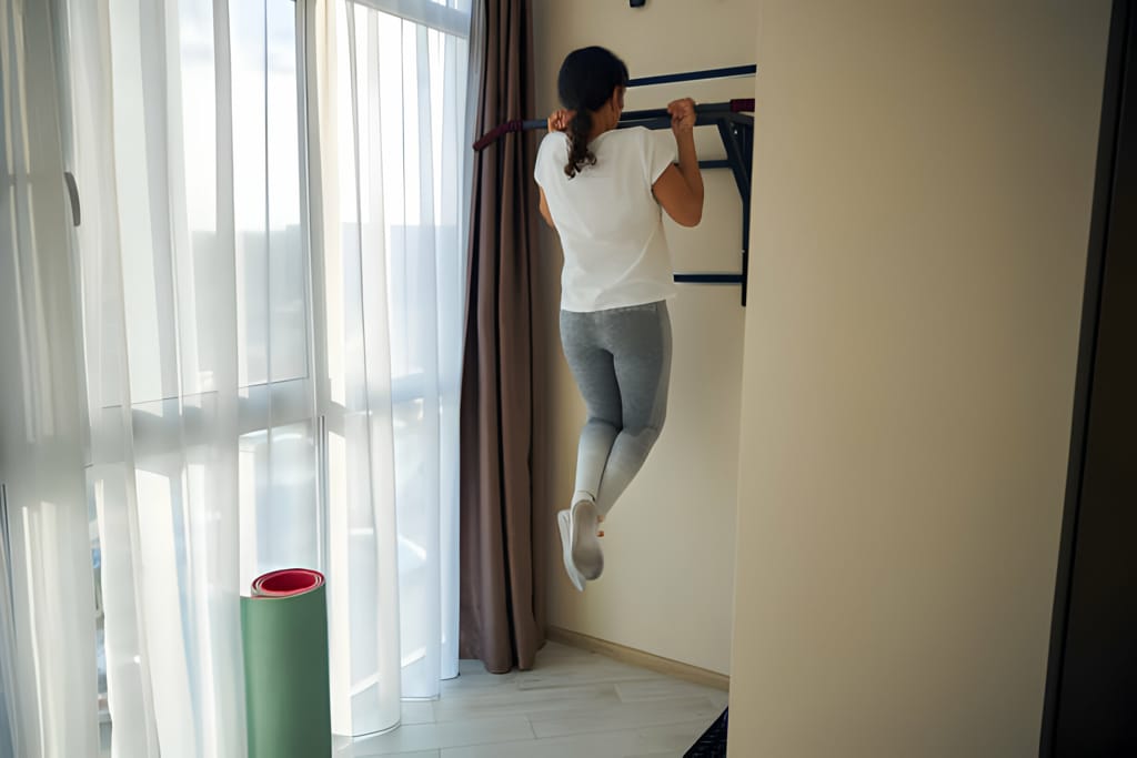 Femeie efectuând exerciții pe o bară de tracțiuni în interior