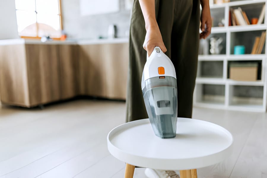 Folosirea unui aspirator de mână pentru curățarea unei mese rotunde