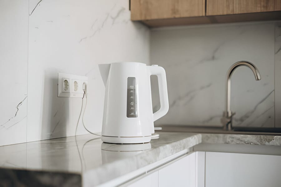Fierbător electric alb pe o masă de bucătărie modernă