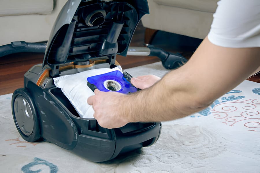 Bărbat schimbând sacul de praf dintr-un aspirator cu sac