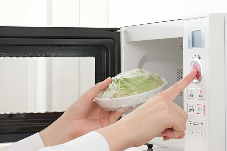 Persoană folosind un cuptor cu microunde pentru a încălzi alimente.