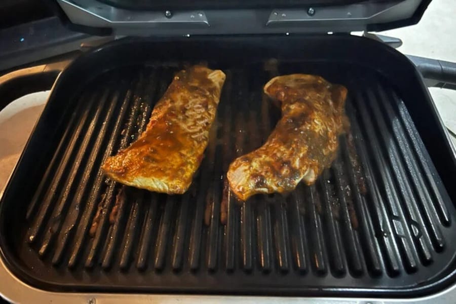 Două bucăți de carne gătindu-se pe un grătar electric Ninja Woodfire