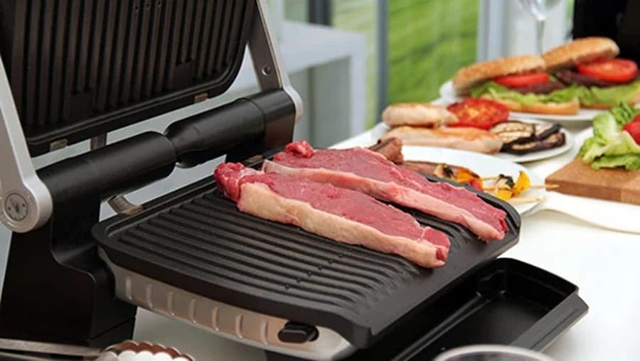 Două bucăți de carne gătindu-se pe un grătar electric Tefal Optigrill