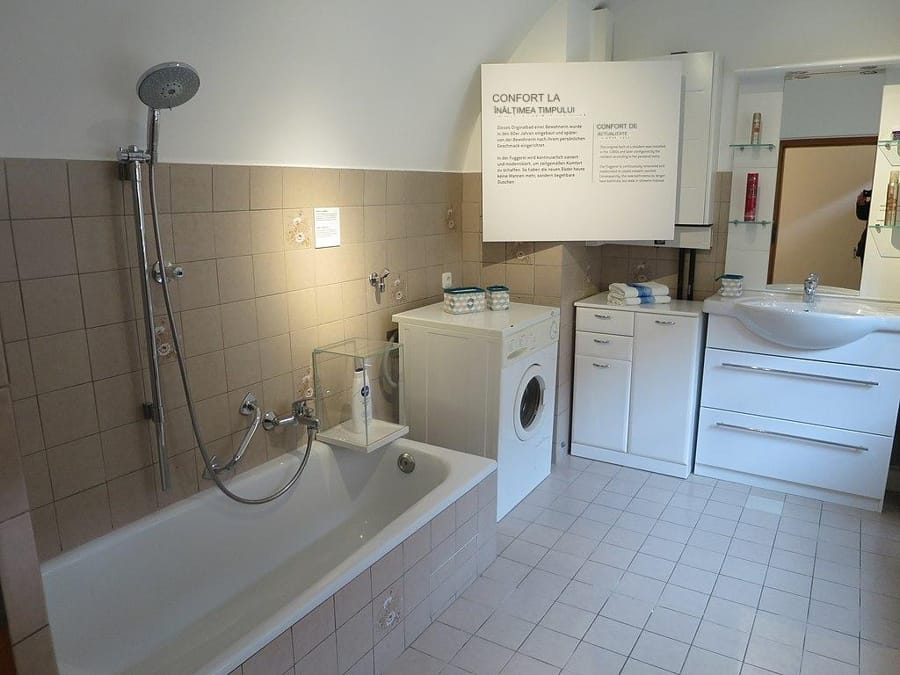 Cadă de baie modernă într-o baie funcțională, cu mașină de spălat integrată.