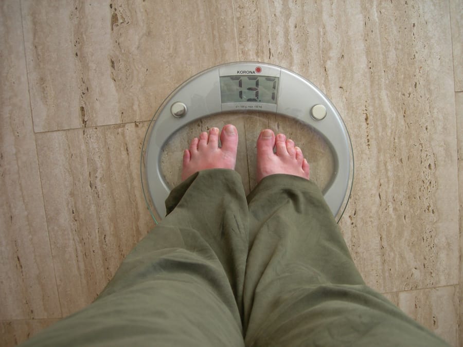 Persoană care se cântărește pe un cântar digital modern.