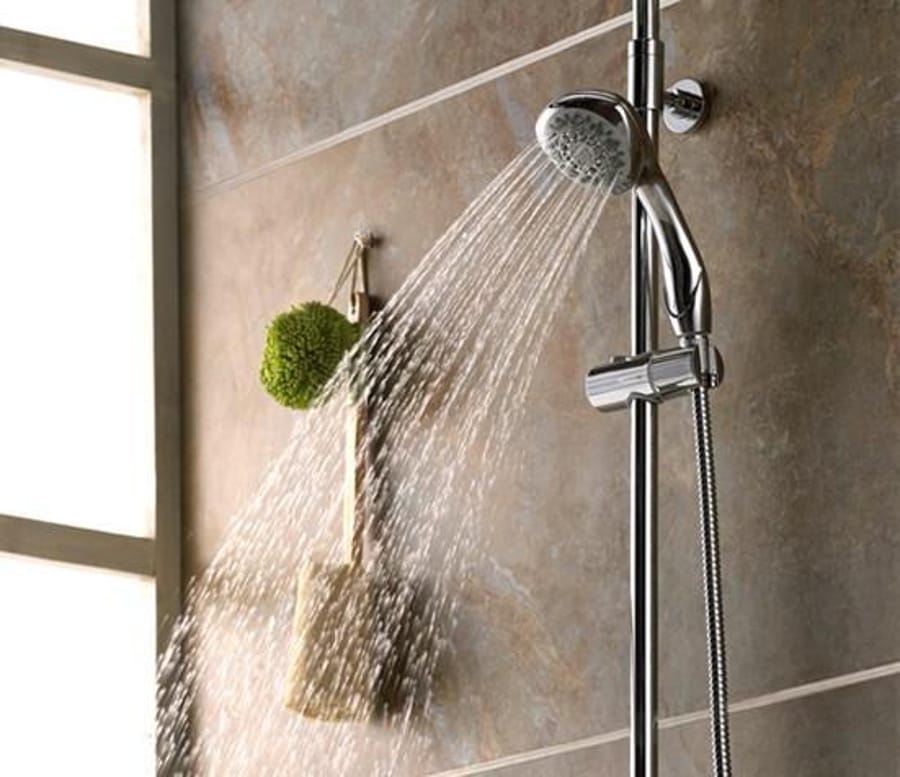 Coloană de duș cu duș de mână montată pe perete, cu jeturi de apă pornite.