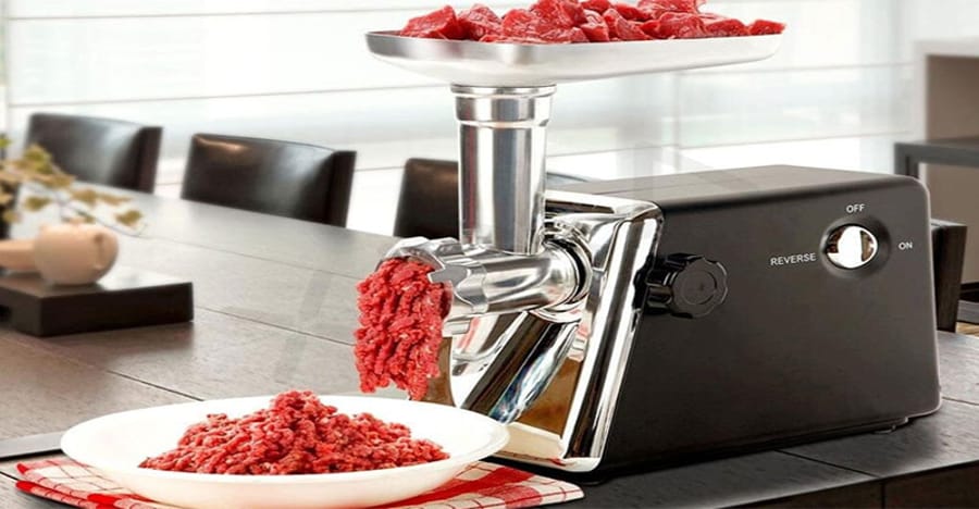 Mașină de tocat carne electrică de culoare neagră, cu carne tocată ieșind într-o farfurie