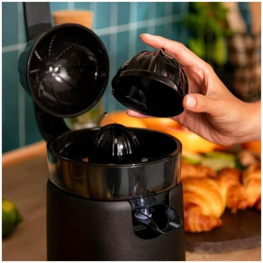 Storcător de citrice negru, cu o mână arătând conul de stoarcere.