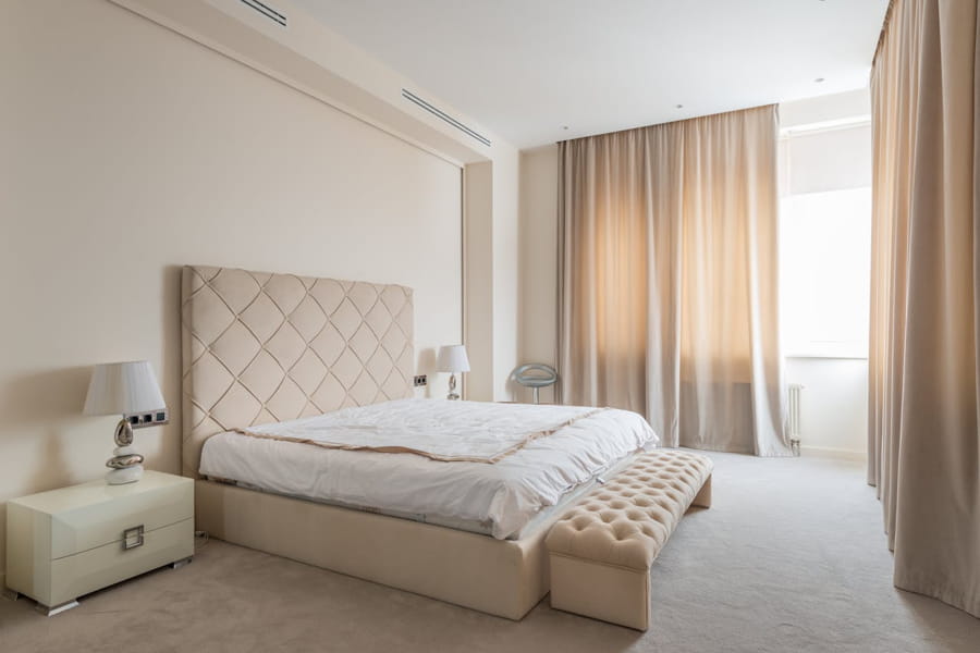 Dormitor elegant cu pat tapițat și noptiere moderne, într-un decor neutru