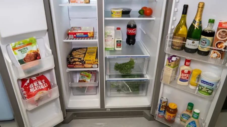 Interiorul unui frigider side by side cu alimente organizate pe rafturi și în uși