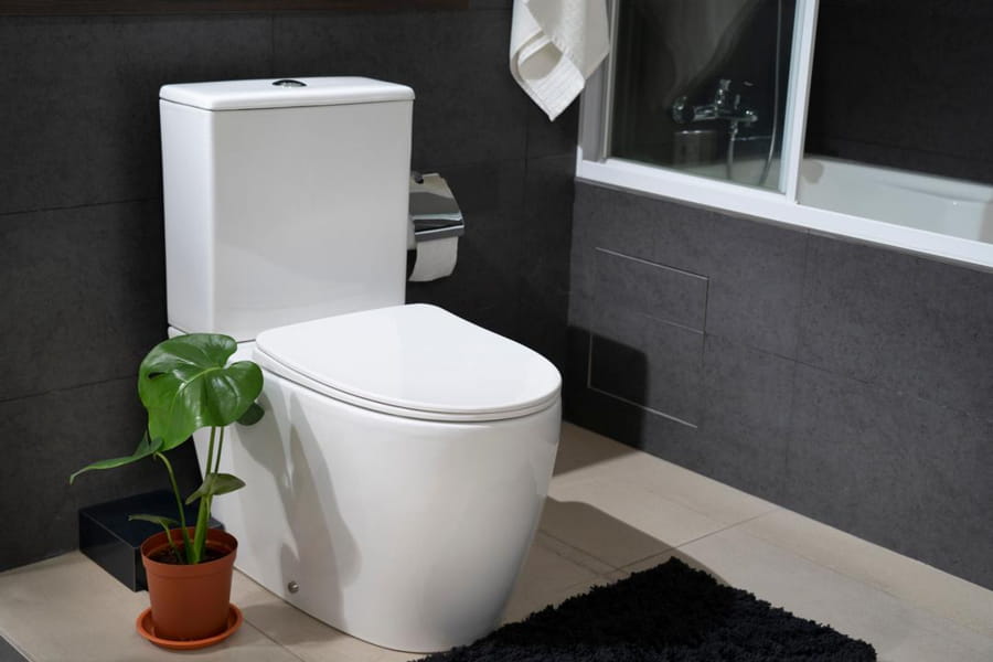 Vas WC de pardoseală alb într-o baie modernă cu finisaje negre