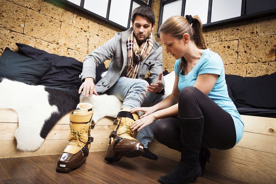 Bărbat probând clăpari de ski sub îndrumarea unei asistente