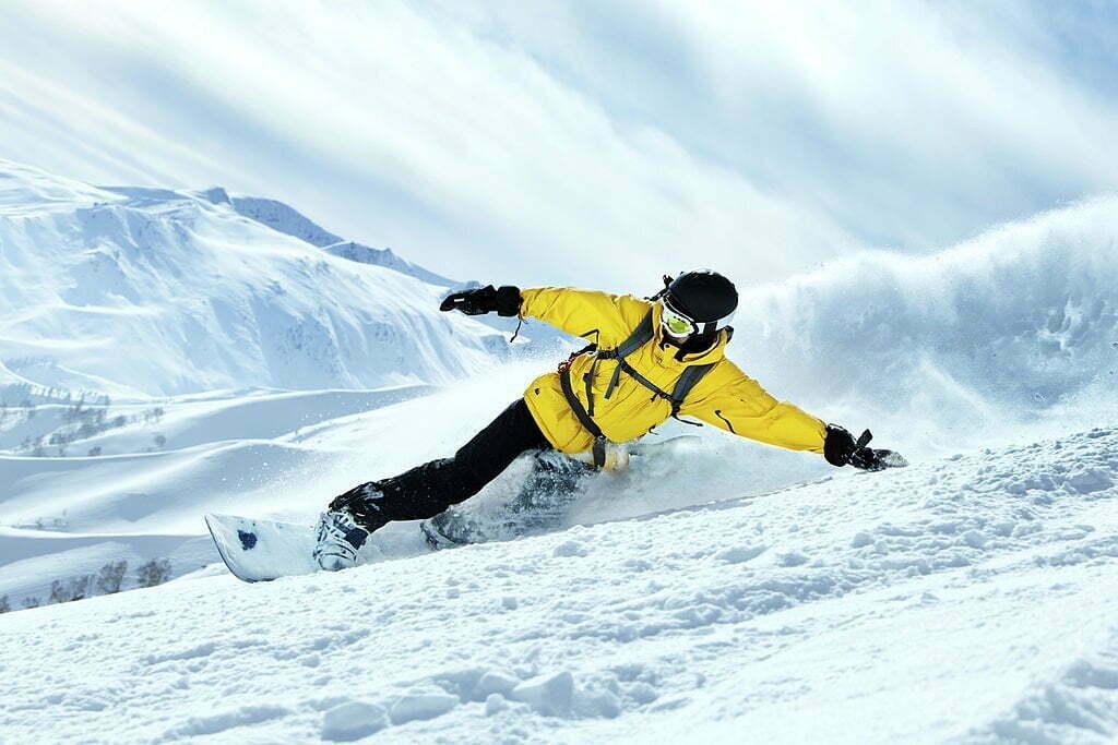 Snowboarder în acțiune pe munte cu o placă de snowboard performantă