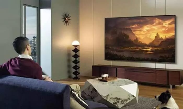 Televizor Samsung montat pe perete într-un living modern, oferind o experiență cinematică