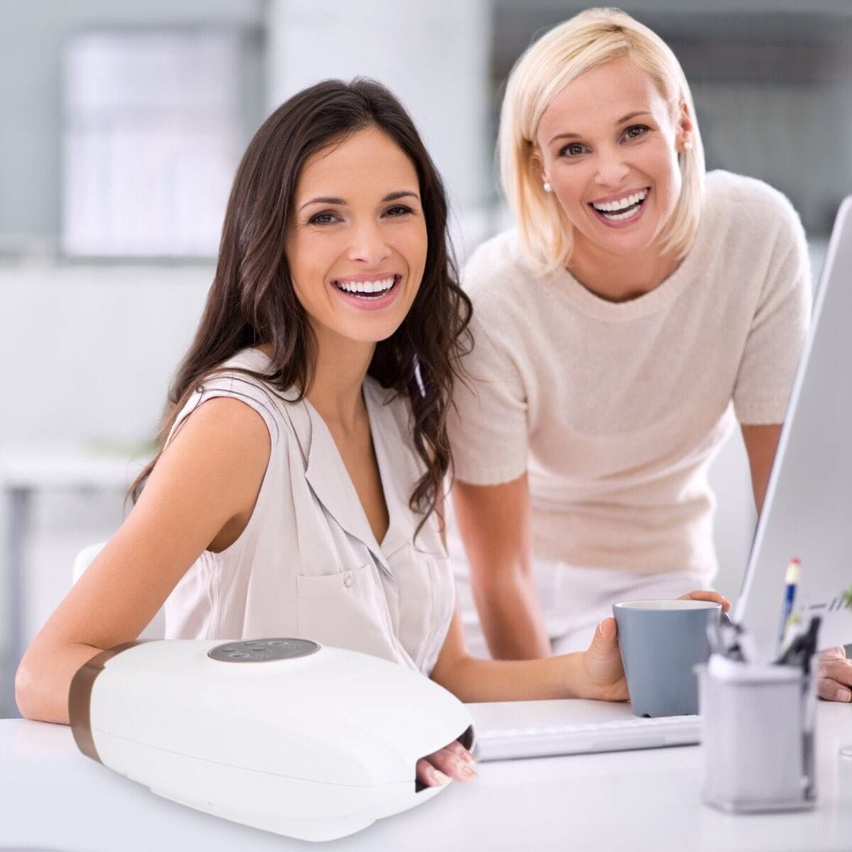 Femeie folosind un aparat de masaj pentru mâini în timp ce lucrează la birou