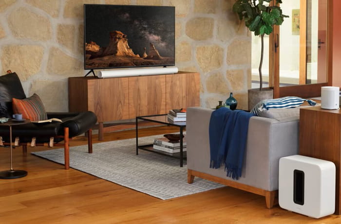 Soundbar elegant alb, integrat într-un living modern cu un subwoofer și decor minimalist