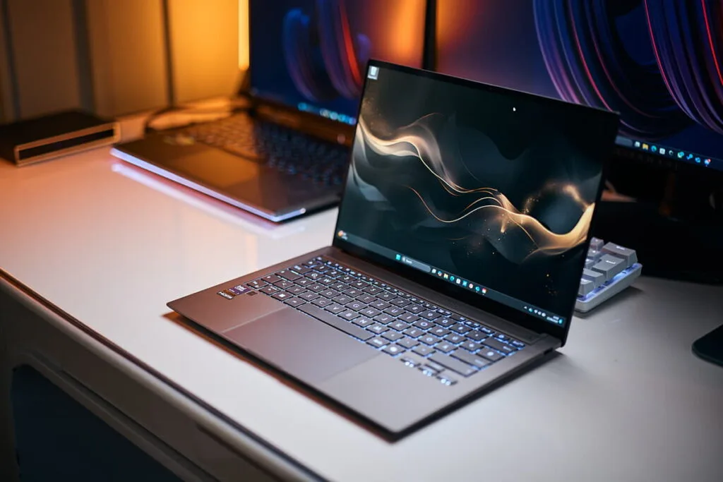 Laptop modern pe birou iluminat, reprezentând cele mai bune laptopuri