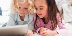 Doi copii folosind o tabletă, ideala pentru educație și divertisment