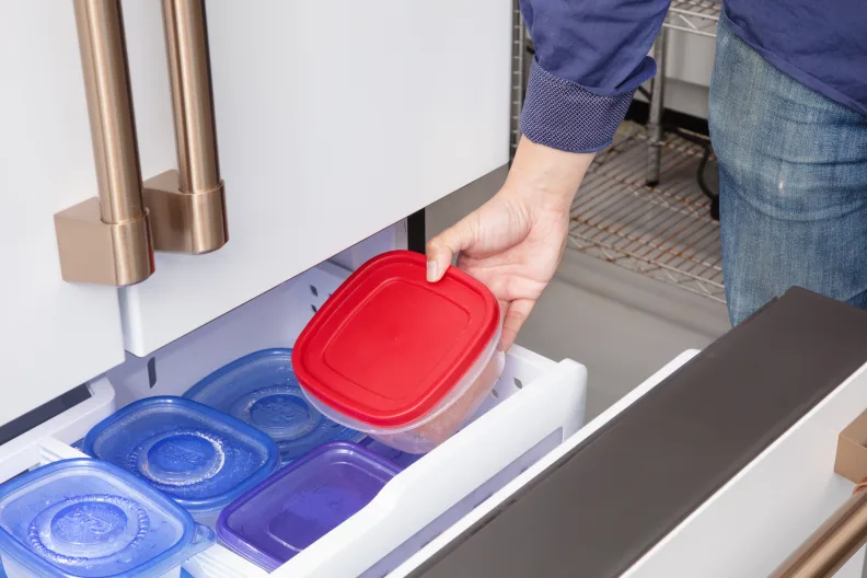 Persoană care organizează alimente într-un congelator inferior