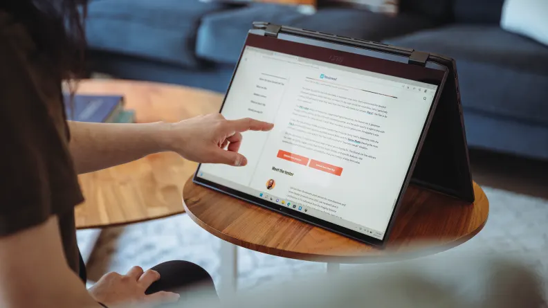 Utilizator navigând pe un laptop convertibil, folosit pentru sarcini zilnice simple