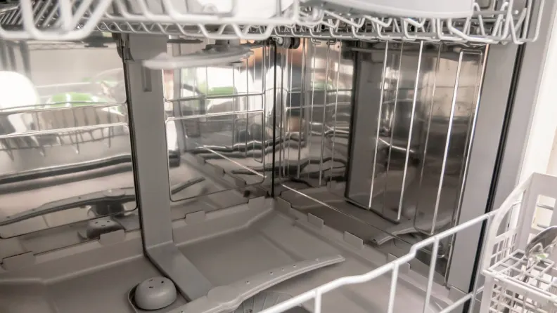Interiorul unei mașini de spălat vase cu cuvă din inox și bază din plastic