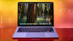 Apple MacBook Air 13 M4 (2025) deschis pe birou, ecran cu pădure în fundal