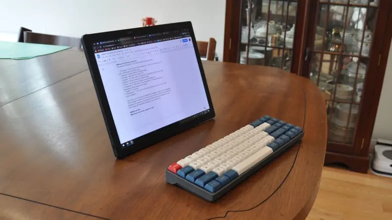 Laptop Lenovo ThinkPad X1 Fold folosit în modul tabletă, pe o masă din lemn