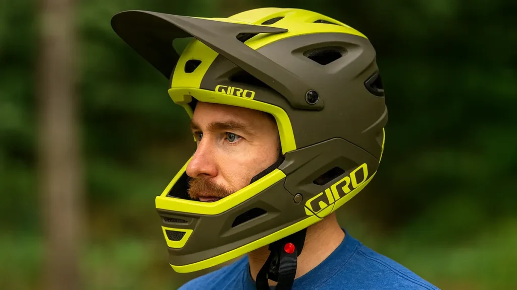 Biker purtând o cască full-face de mountain bike, fotografiat din profil în pădure