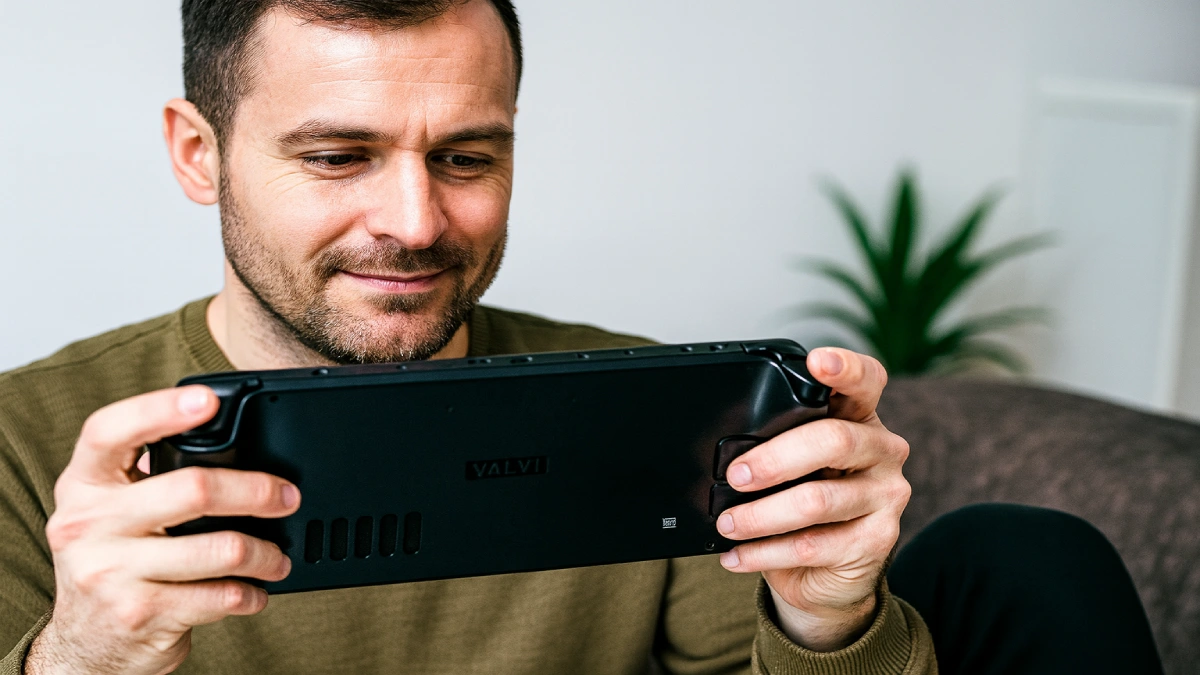 Bărbat tânăr jucând pe o consolă portabilă de gaming, folosit ca ilustrație pentru evaluarea echipamentelor și periferialelor de gaming.