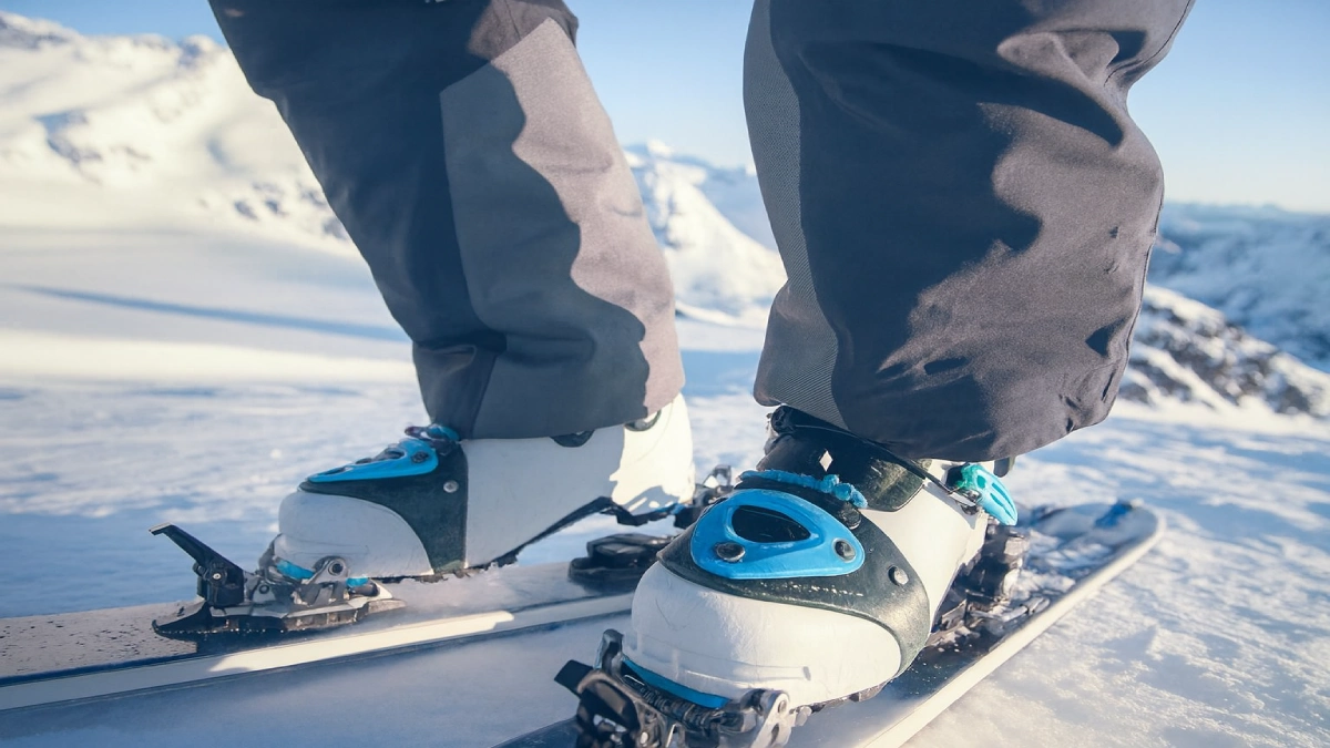 Clăpari de schi eliberați din legături, surprinși pe schiuri în zăpadă, cu mecanismul de siguranță vizibil