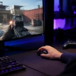 Gamer apăsând click pe mouse gaming în fața unui monitor cu joc rapid pe ecran, setup cu lumină RGB albastru-violet